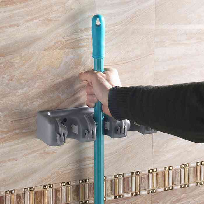 Hand placing mop into Plastic Mop Hook – Wall Hanging Multifunctional Cabinet Holder mounted on tiled wall. Perfect for organizing cleaning tools efficiently.